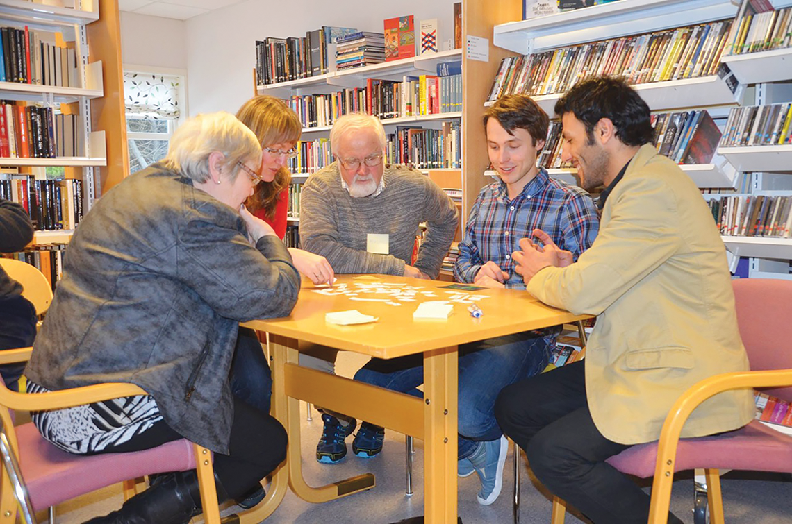 Hver fredag arrangeres Språkkafé, et samarbeid mellom biblioteket, flyktningetjenesten og frivillige. Da møtes frivillige og mennesker med innvandrerbakgrunn som ønsker å prate norsk. På bildet forsøker de å finne ord som passer til et bilde av nordlys. F